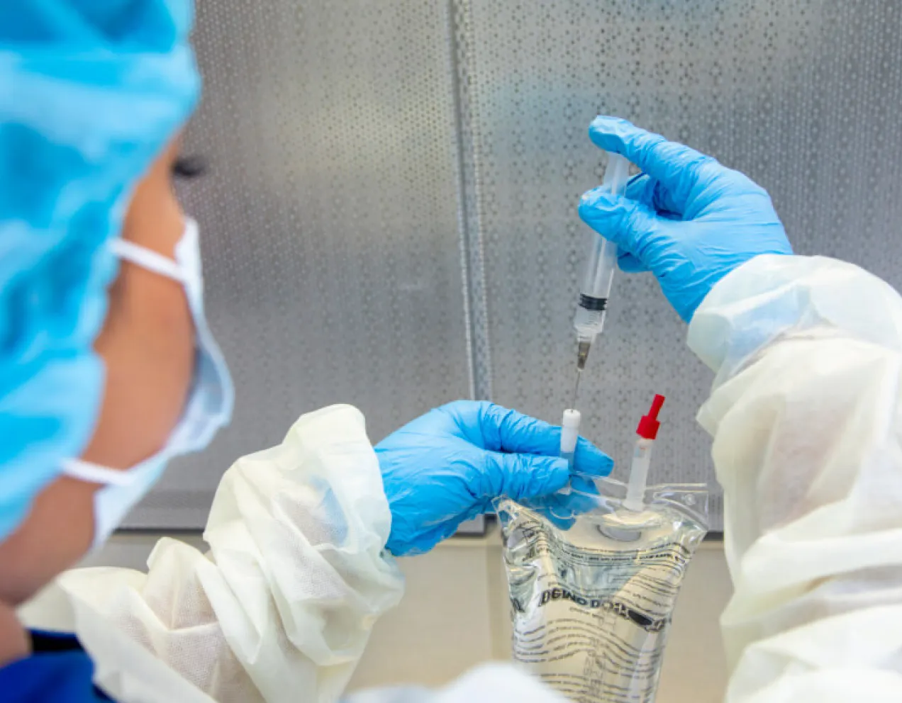 Pharmacy technician preparing medication with syringe and IV bag in sterile environment, showcasing certification skills.
