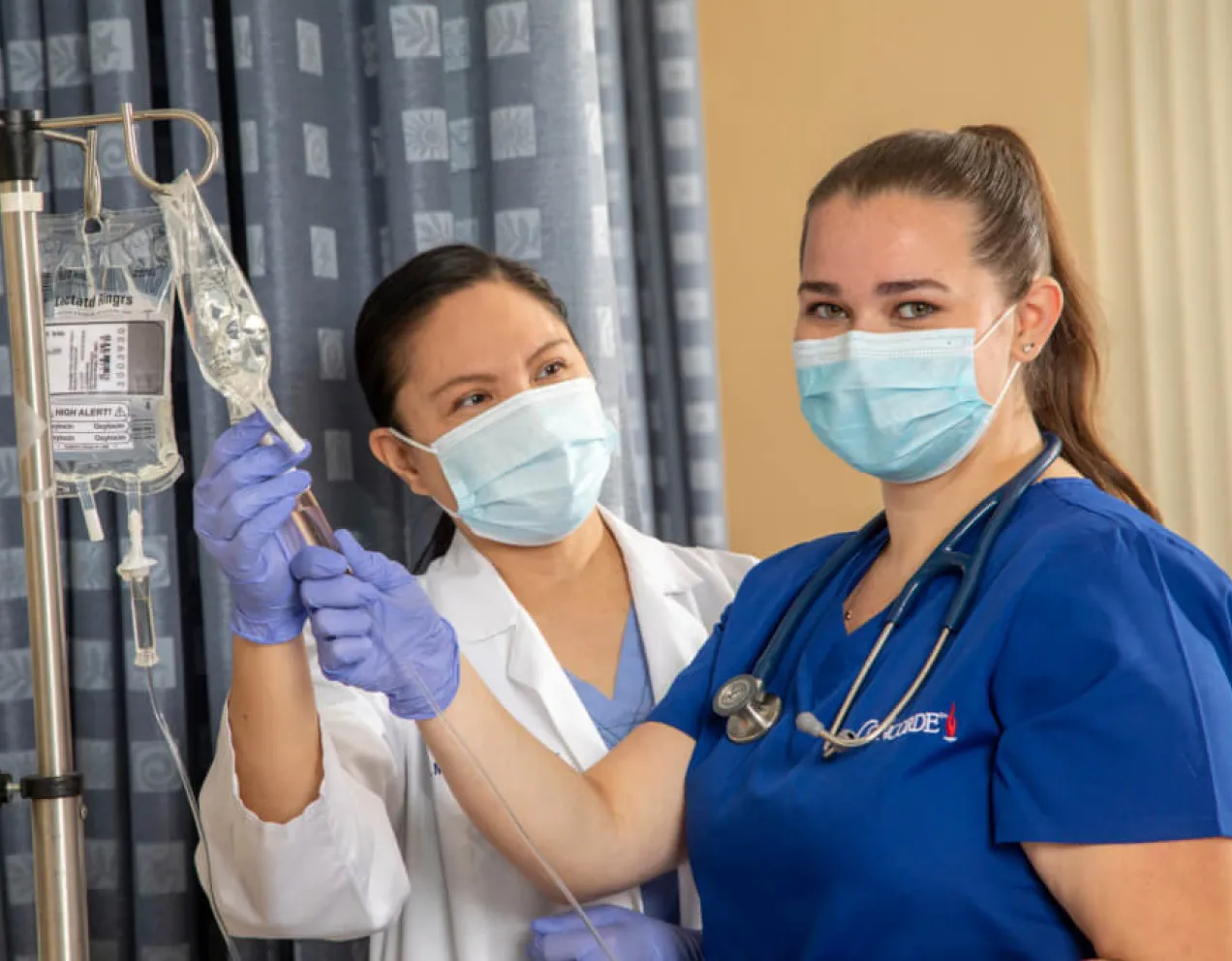 Nursing student learning to check IV fluid levels during hands-on training session