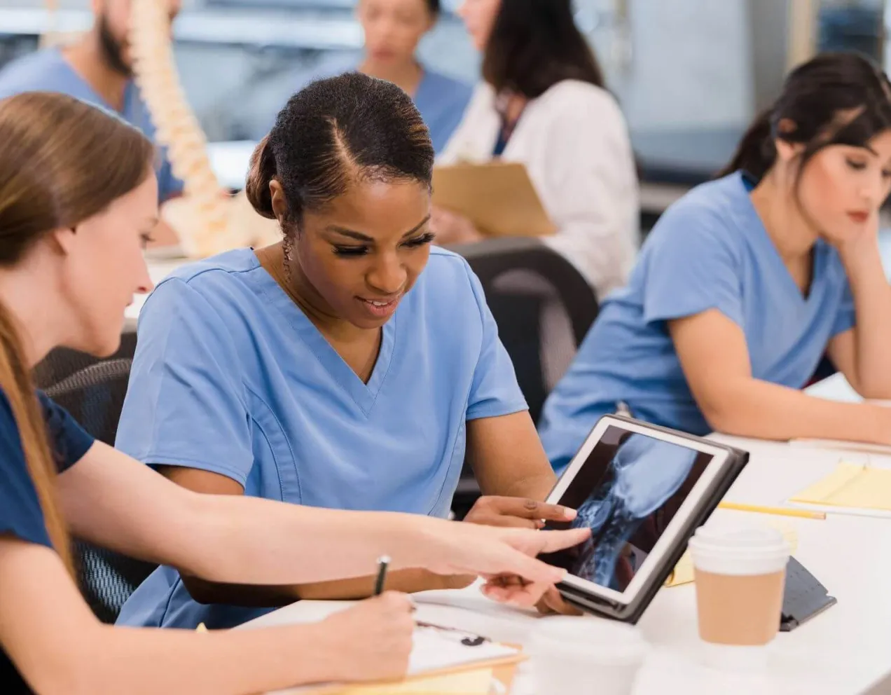 Radiologic technology students review spinal X-ray on tablet during class, preparing for hands-on healthcare careers