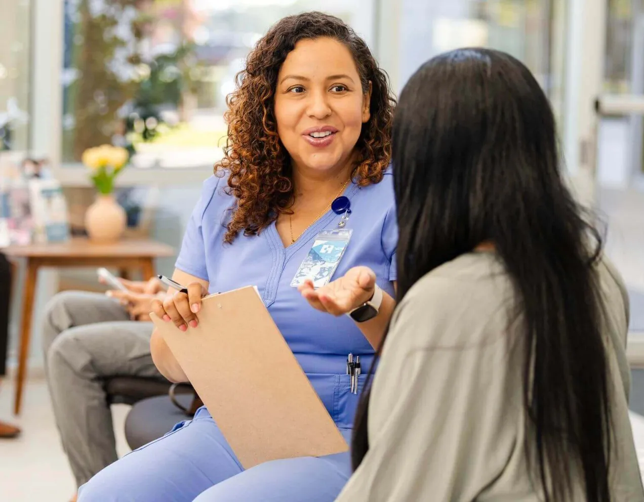 Medical office specialist speaking with patient in a clinic waiting room, highlighting the role's communication and support duties