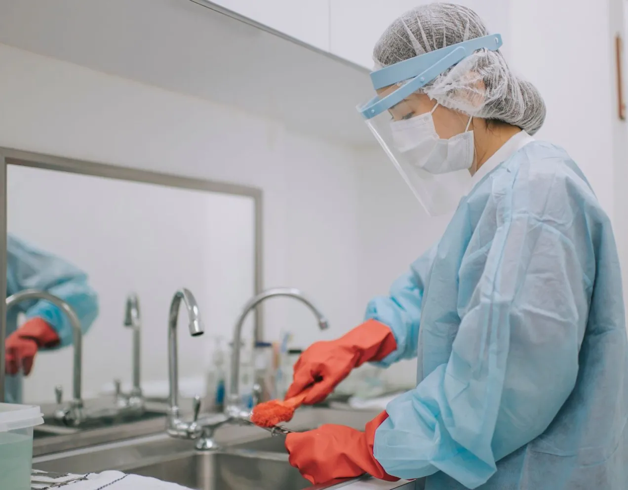Sterile processing technician cleaning surgical tools at a sink, representing job responsibilities and outlook
