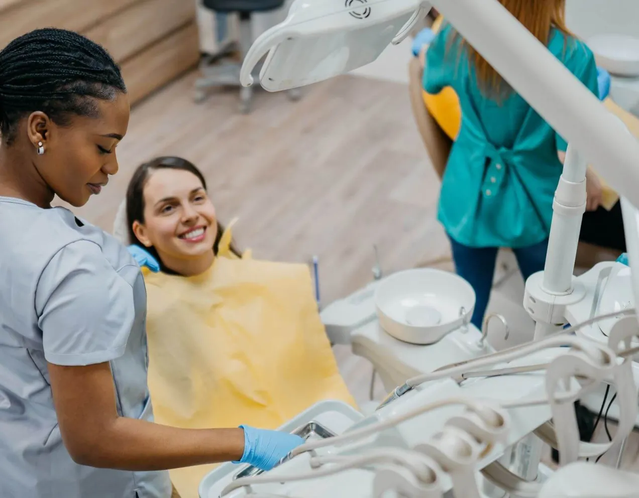 Dental assistant helping a patient in the dental chair during a clinical procedure, reflecting patient care responsibilities in the role.
