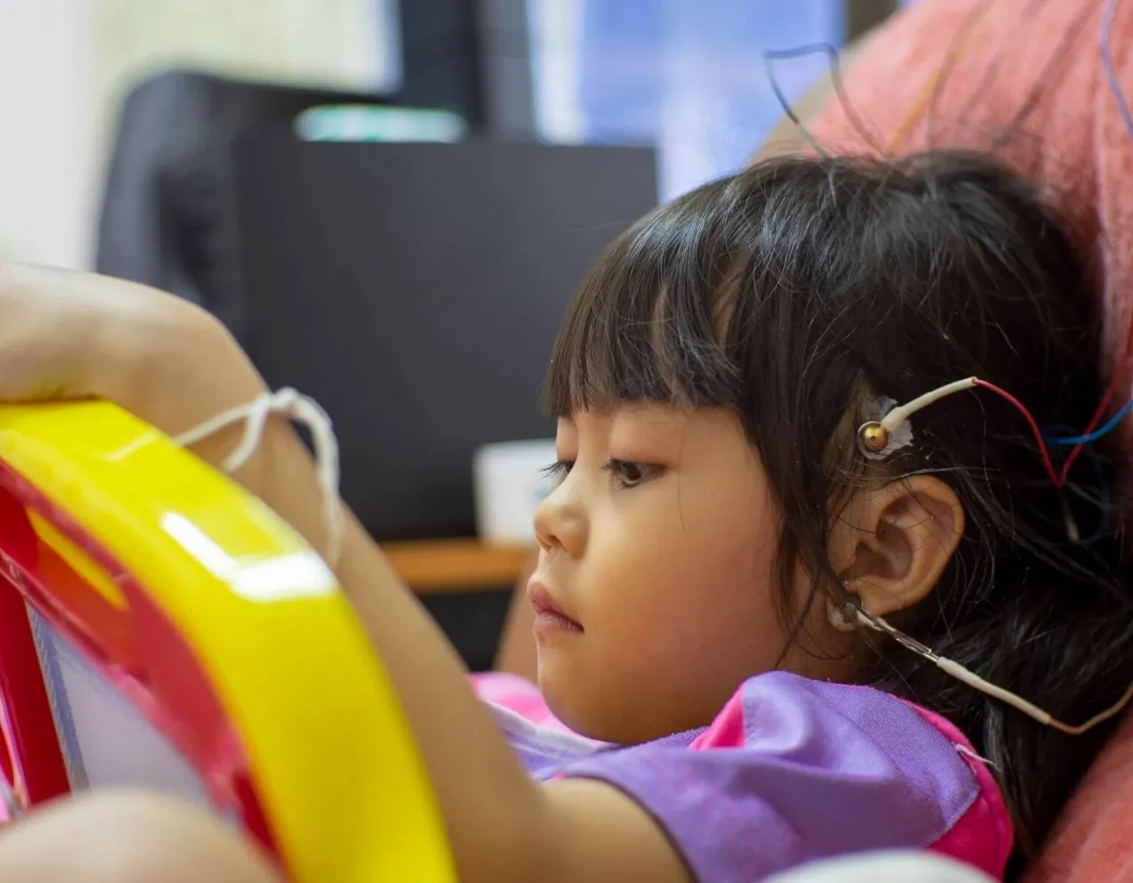 A Neurodiagnostic Technologist performs an electroencephalogram (EEG) on a young child, placing electrodes on the scalp as part of their clinical training for a key neurodiagnostic course.