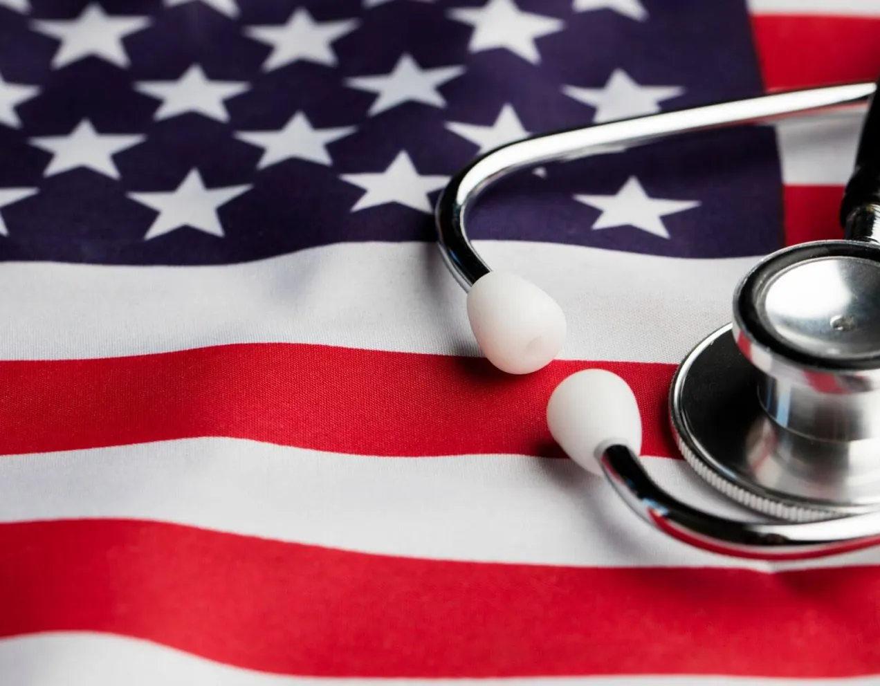 A medical stethoscope rests on top of a draped United States flag, symbolizing the career path transition from a military medic to a registered nurse.
