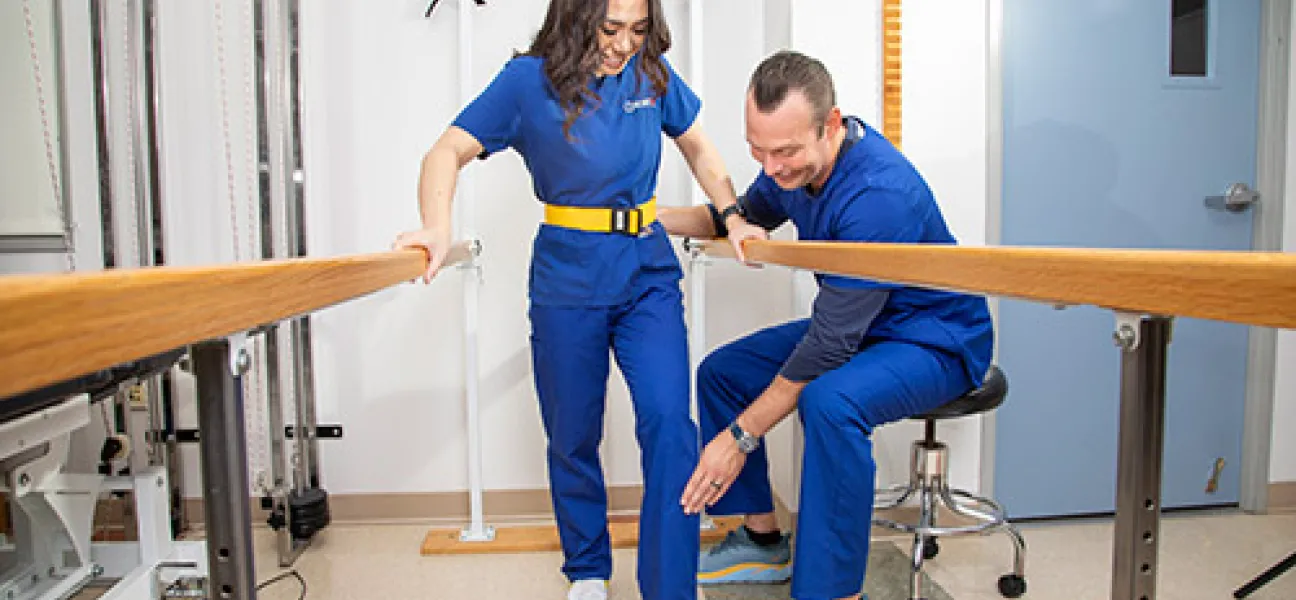 Physical therapist assistant student learning proper assisted walking technique