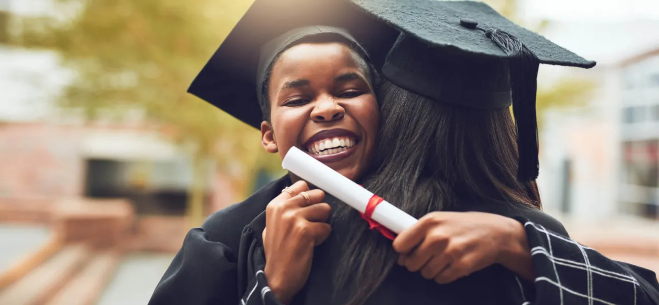 Graduate in cap and gown getting a celebratory hug.