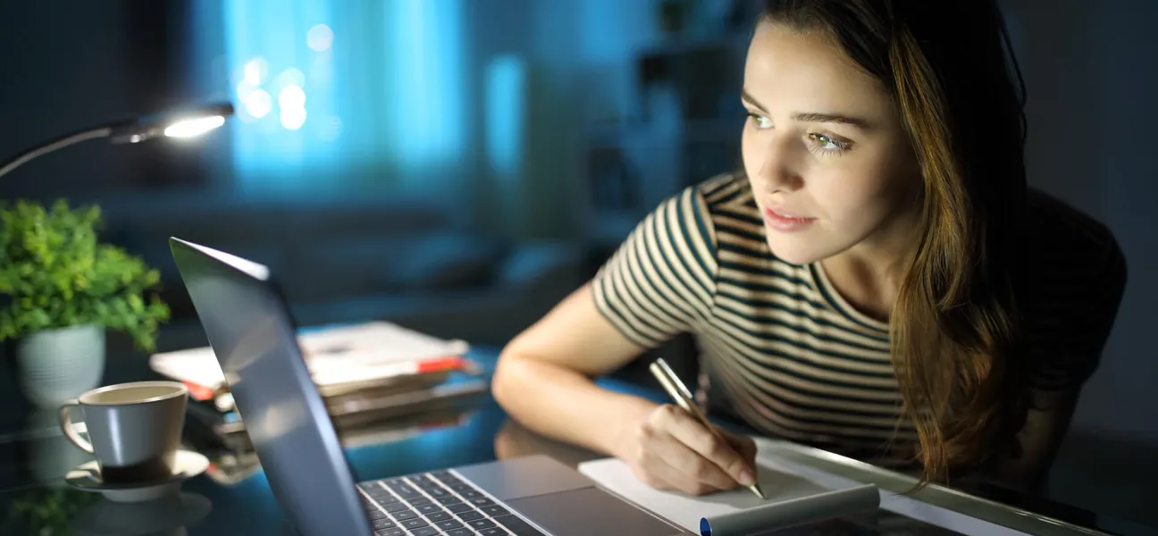 Young working woman studying on computer at night.