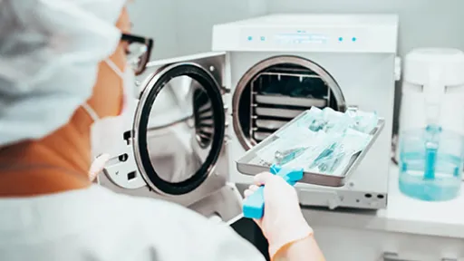 A sterile processing technician loads medical instruments into an autoclave