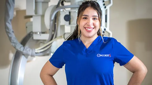 A radiologic tech stands in front of an x-ray imaging machine.
