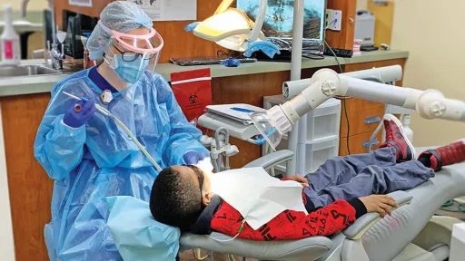 A dental hygienist performs a routine cleaning on young male patient.