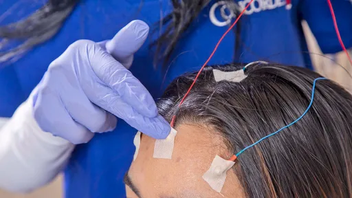 A neurodiagnostic technologist puts electrodes on patient's forehead.