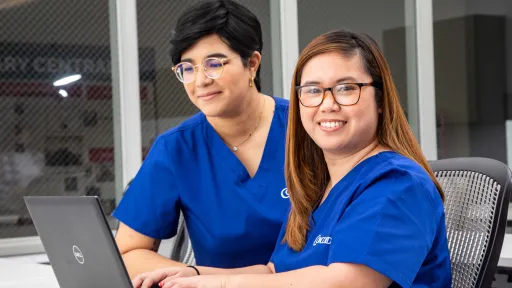 Medical office administrators reviewing files on laptop.