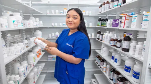 Pharmacy technician organizing medication on shelves.