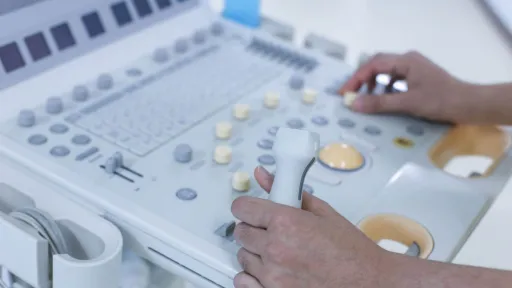 Close-up of echocardiogram technician operating ultrasound machine controls during a cardiac imaging procedure.