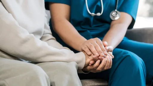 Nurse providing emotional support by holding a patient’s hand, highlighting compassion in nursing jobs.