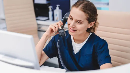Medical office administrator speaking on the phone at a front desk
