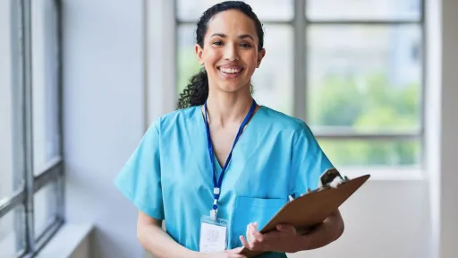 Smiling medical office specialist holding clipboard, representing career growth and advancement opportunities in healthcare