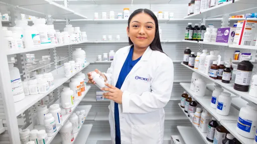 Student in a pharmacy lab learning medication organization and labeling as part of training.