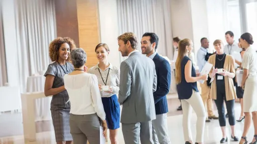 Travel nurse networking with healthcare and business professionals at a career event, building connections to support a successful travel nursing career