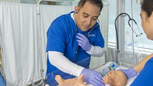 A male respiratory therapist uses stethoscope to listen to a baby's breathing