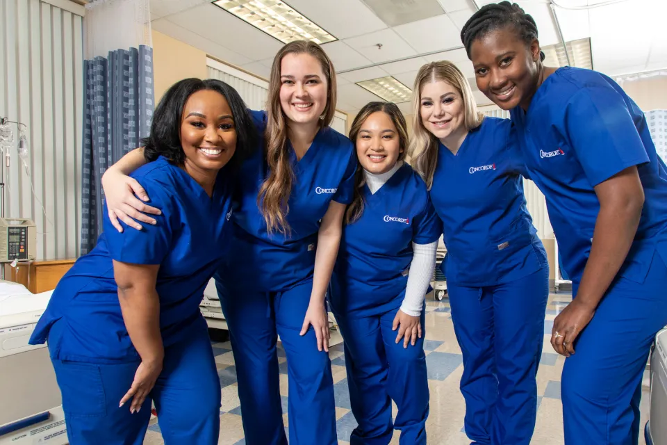 Concorde nursing students in scrubs pose together in a clinical lab, representing Oregon workforce training partnerships