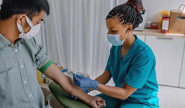 A phlebotomist prepares her patient's left arm before drawing blood.