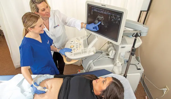 Diagnostic medical sonographer performs ultrasound on expecting mother.
