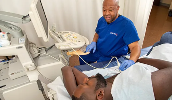 A cardiovascular sonographer performs cardiac ultrasound on patient.