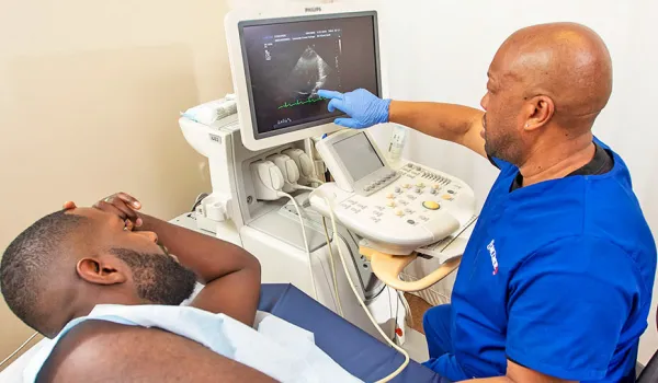 Cardiac sonographer with patient points to image on screen.