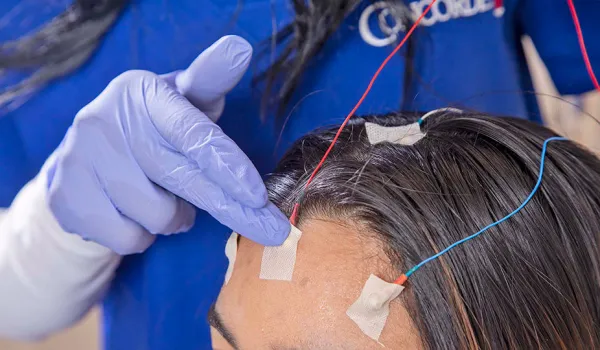 A neurodiagnostic technologist puts electrodes on patient's forehead.