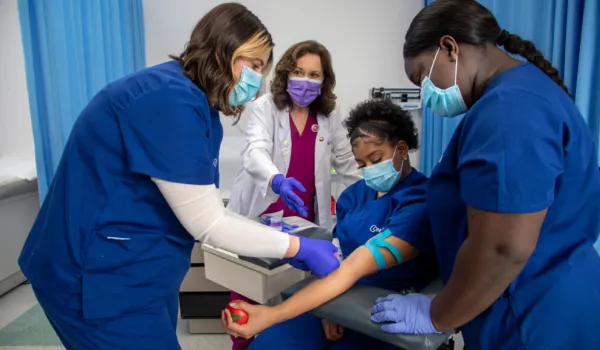 Medical assistant students practicing phlebotomy skills during hands-on training in a clinical education lab setting.