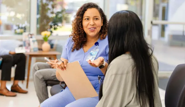 Medical office specialist speaking with patient in a clinic waiting room, highlighting the role's communication and support duties