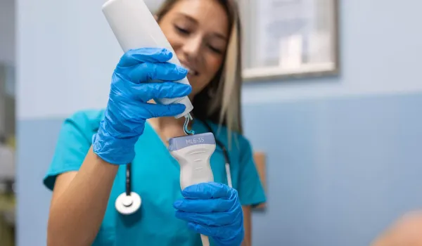 Sonographer applying gel to ultrasound transducer before performing a sonography exam