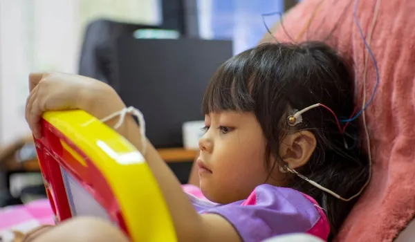 A Neurodiagnostic Technologist performs an electroencephalogram (EEG) on a young child, placing electrodes on the scalp as part of their clinical training for a key neurodiagnostic course.