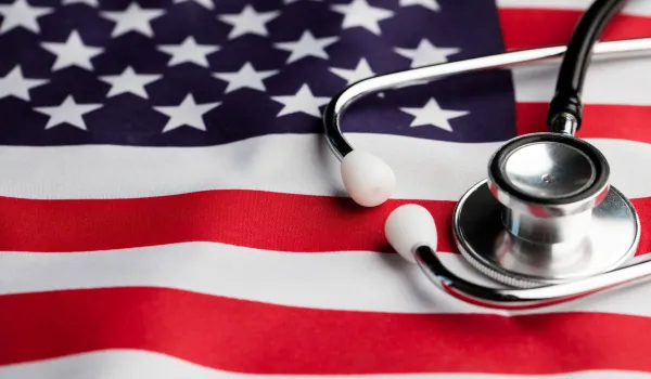 A medical stethoscope rests on top of a draped United States flag, symbolizing the career path transition from a military medic to a registered nurse.
