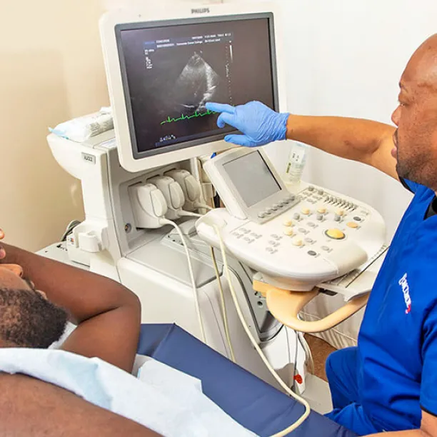 Cardiac sonographer with patient points to image on screen.