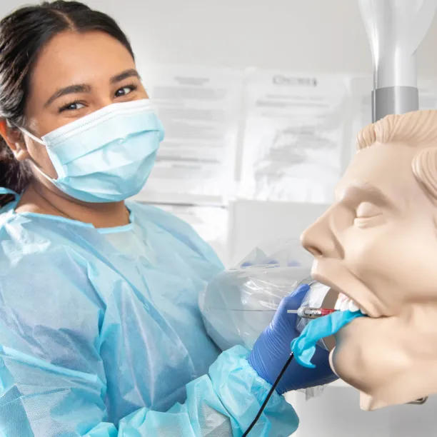 Dental Assistant cleaning the mouth of a dental manekin.
