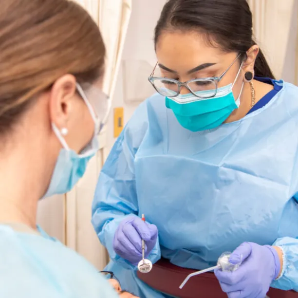 Dental Assistant in scrubs calms patient during procedure with dentist