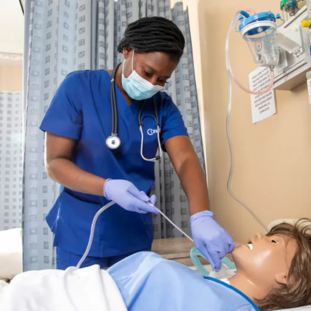 Nursing student performing suctioning procedure on training manikin in lab