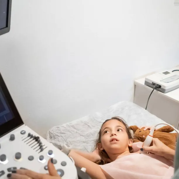 Cardiovascular sonographer performing heart ultrasound on young patient, illustrating diagnostic imaging in cardiac care.