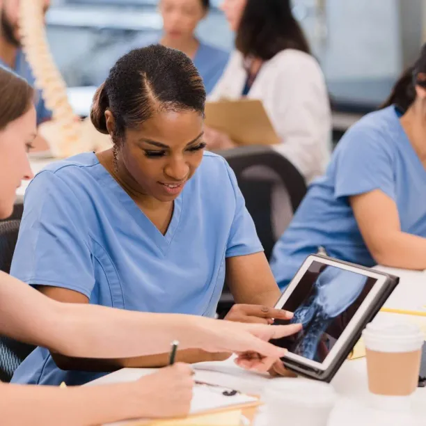 Radiologic technology students review spinal X-ray on tablet during class, preparing for hands-on healthcare careers