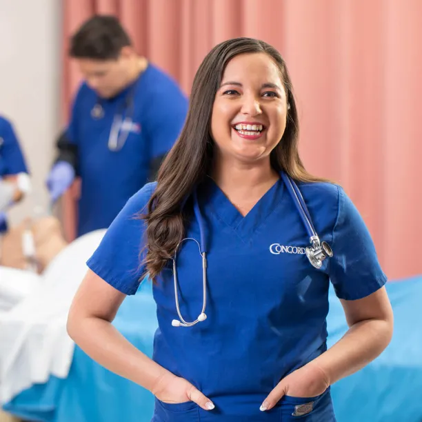 Concorde student smiling as others study respiratory therapy in the background