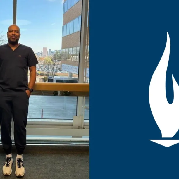 JR in navy blue scrubs standing proudly in the hallway of a hospital
