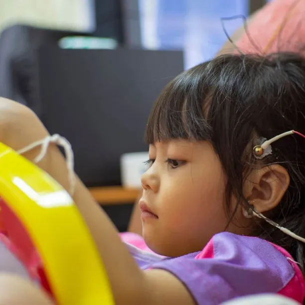 A Neurodiagnostic Technologist performs an electroencephalogram (EEG) on a young child, placing electrodes on the scalp as part of their clinical training for a key neurodiagnostic course.