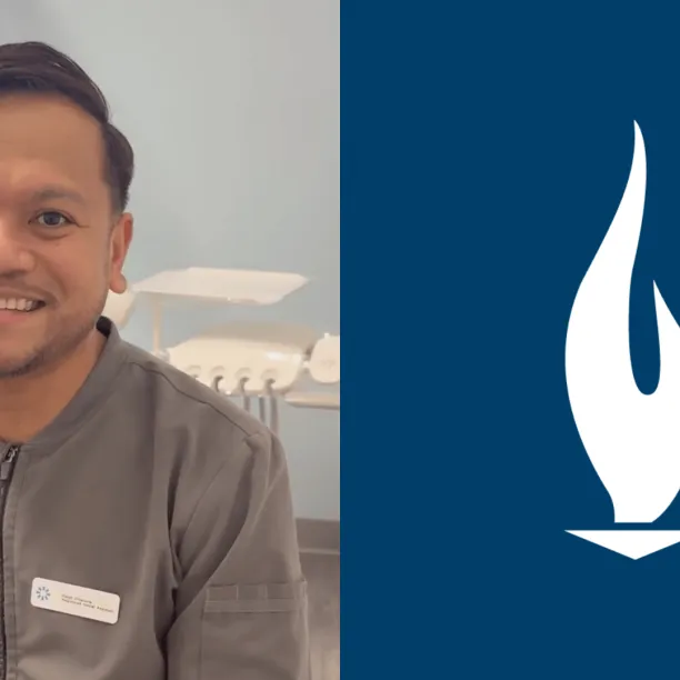 A male dental assistant with brown hair and wearing grey scrubs smiles for camera