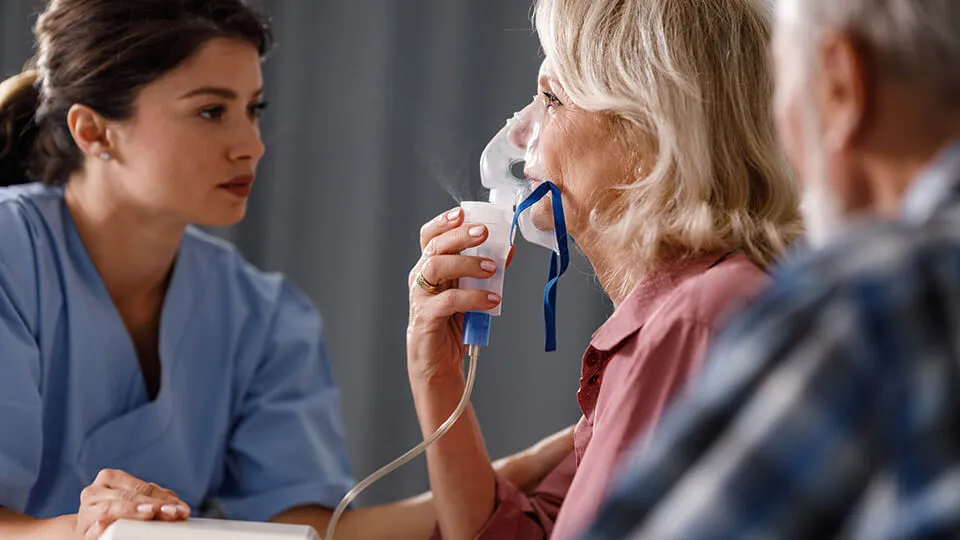 respiratory therapist gives breathing treatment to older woman respiratory therapist gives breathing treatment to older woman