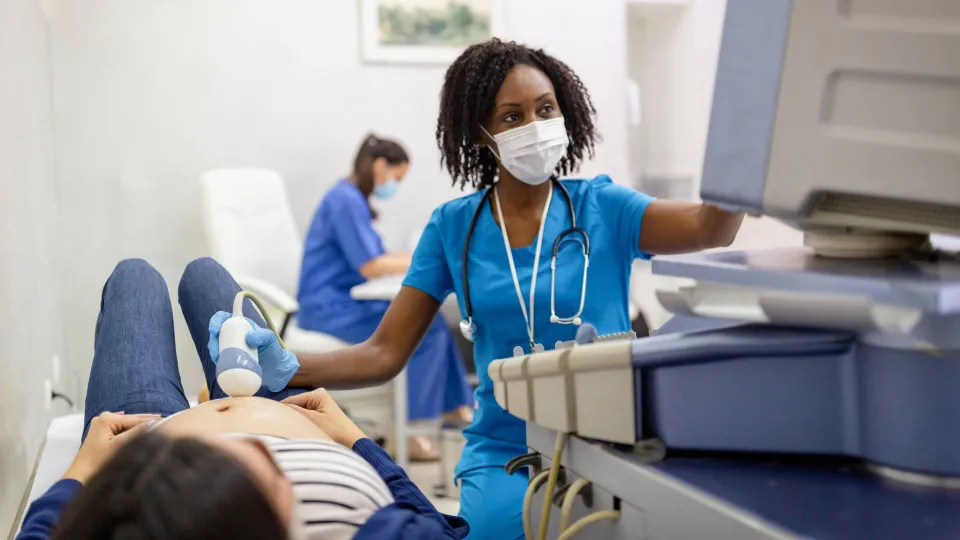 A sonographer look at a computer as she scans the lower abdomen of her patient. A sonographer look at a computer as she scans the lower abdomen of her patient.