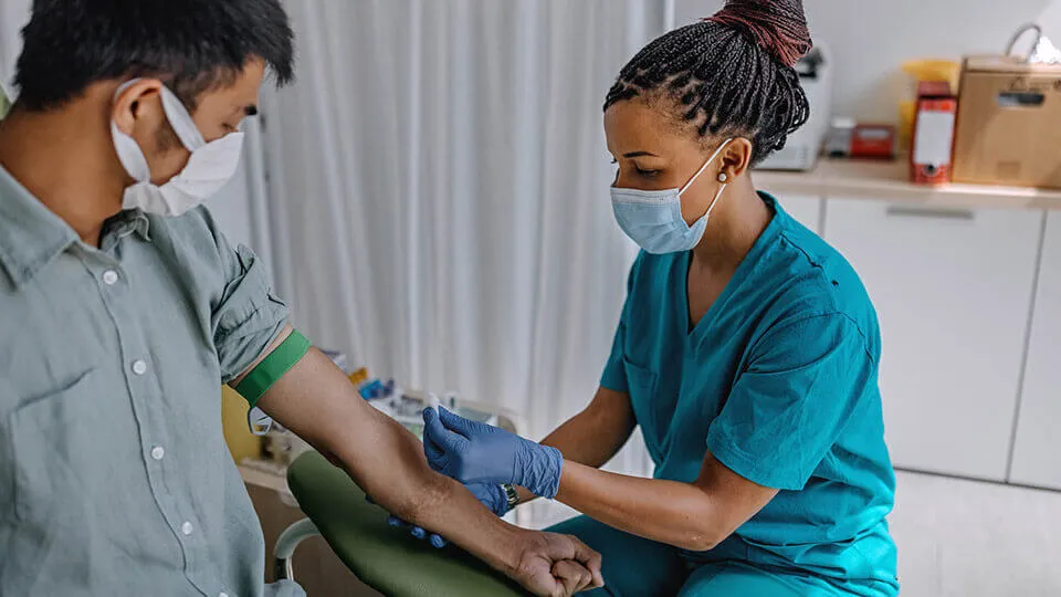 A phlebotomist prepares her patient's left arm before drawing blood. A phlebotomist prepares her patient's left arm before drawing blood.