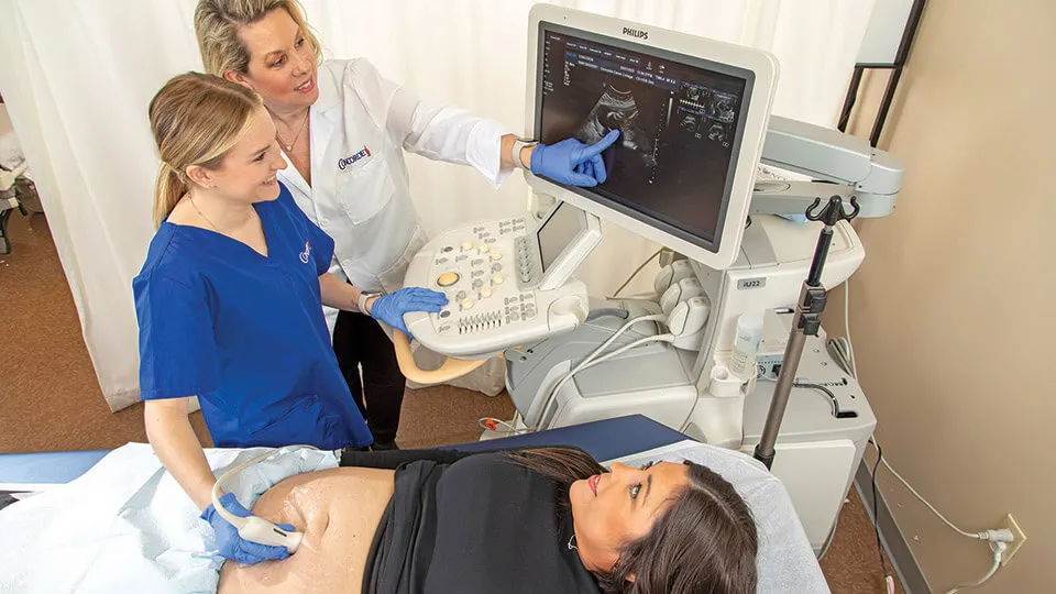 Diagnostic medical sonographer performs ultrasound on expecting mother.