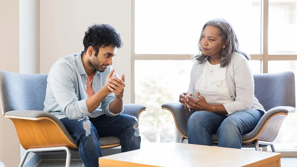 A young man speaks with his mental health provider about an experience that caused a negative emotional reaction. A young man speaks with his mental health provider about an experience that caused a negative emotional reaction.
